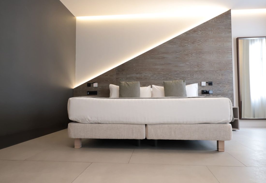 Habitación de hotel con cama grande y cabecera de madera en diagonal