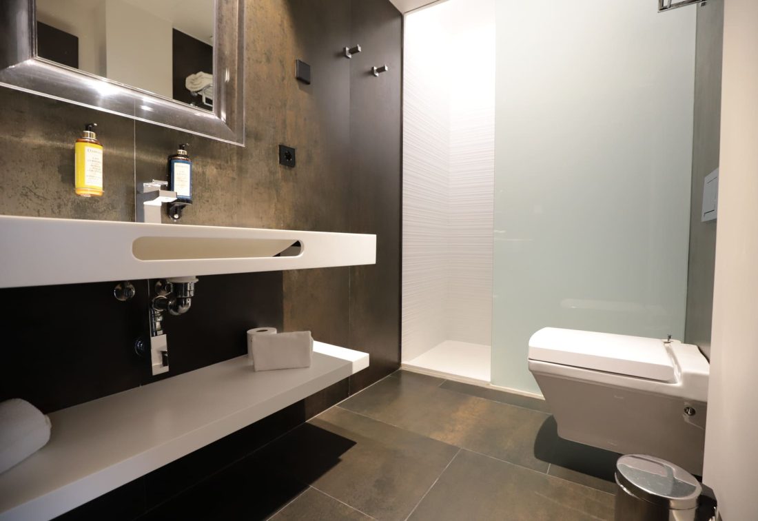 Baño moderno con lavabo suspendido, ducha de vidrio e inodoro