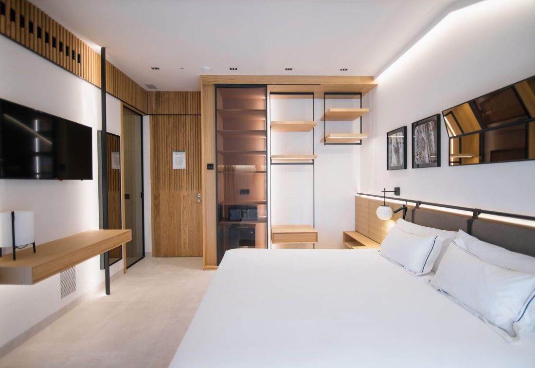Habitación moderna de hotel con cama grande, TV, escritorio y armario abierto