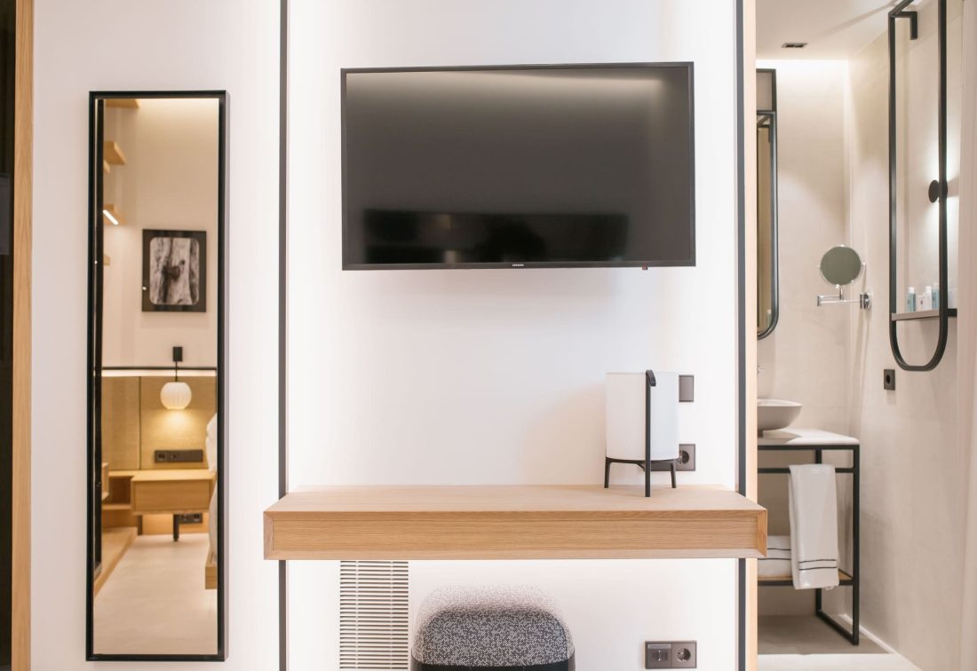 Habitación de hotel con televisor de pared y baño al fondo
