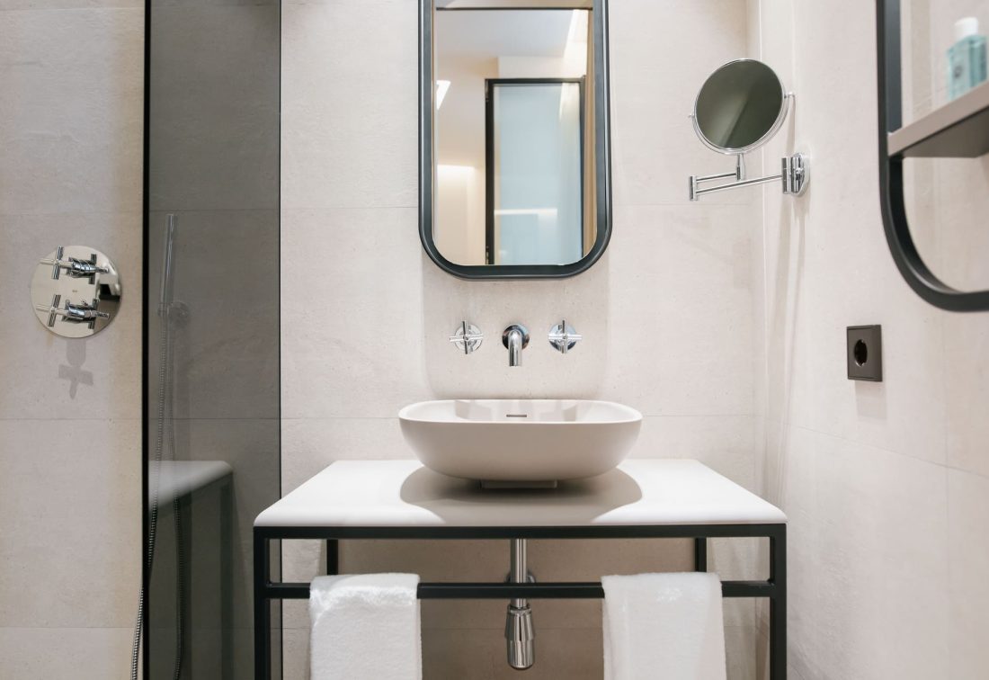 Lavabo ovalado sobre encimena blanca en baño moderno con espejo