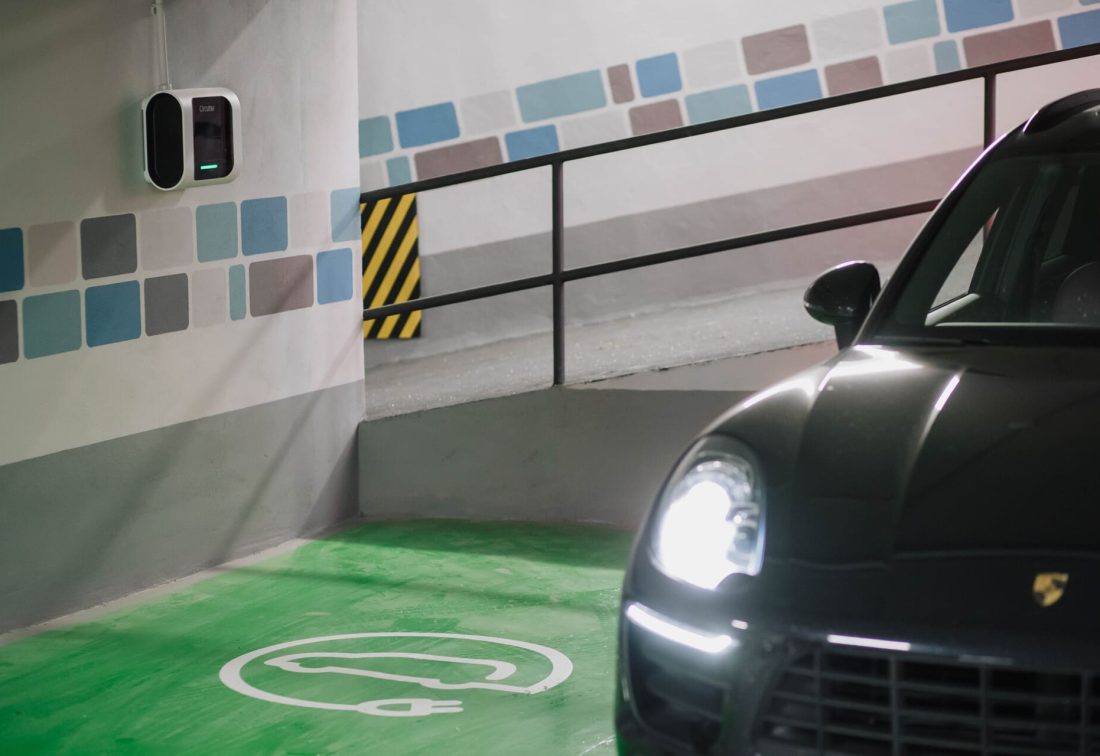 Porsche negro en plaza de carga eléctrica del garaje subterráneo