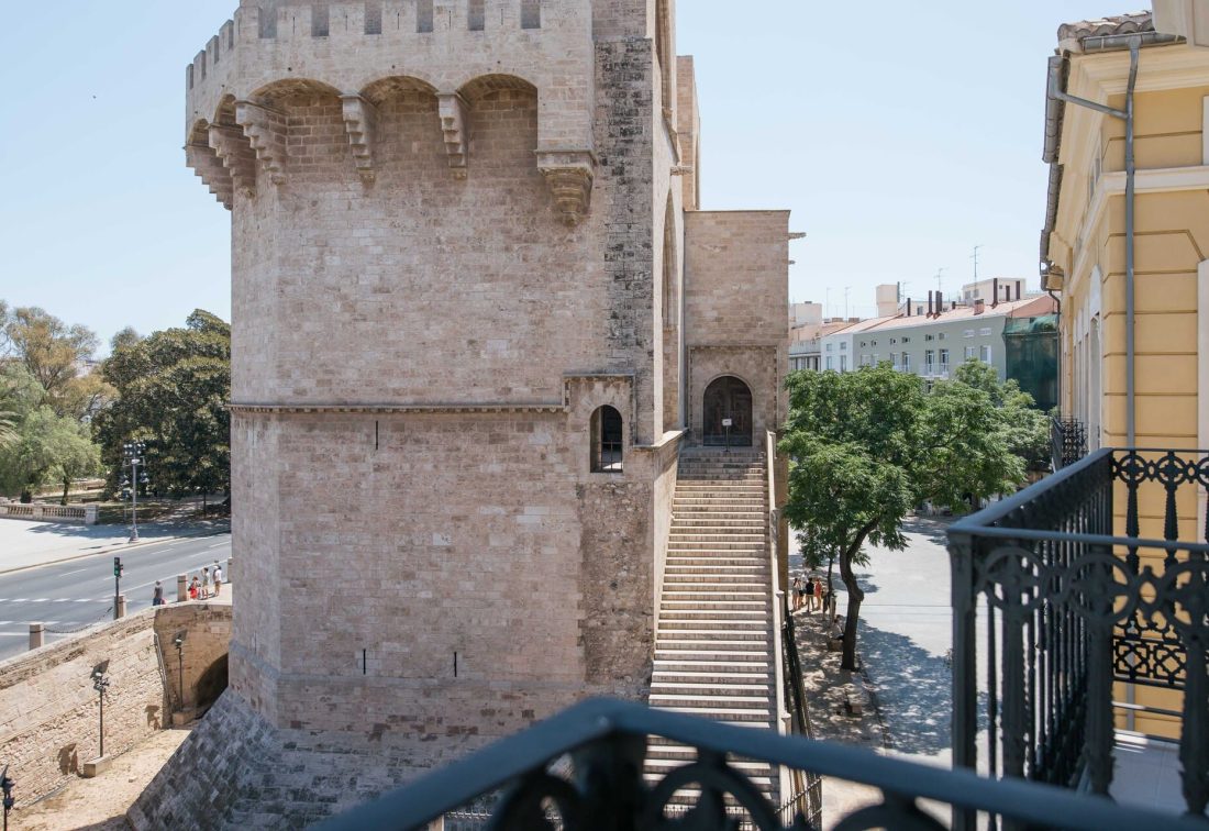 Torre de fortaleza de piedra con escalera exterior y calle urbana