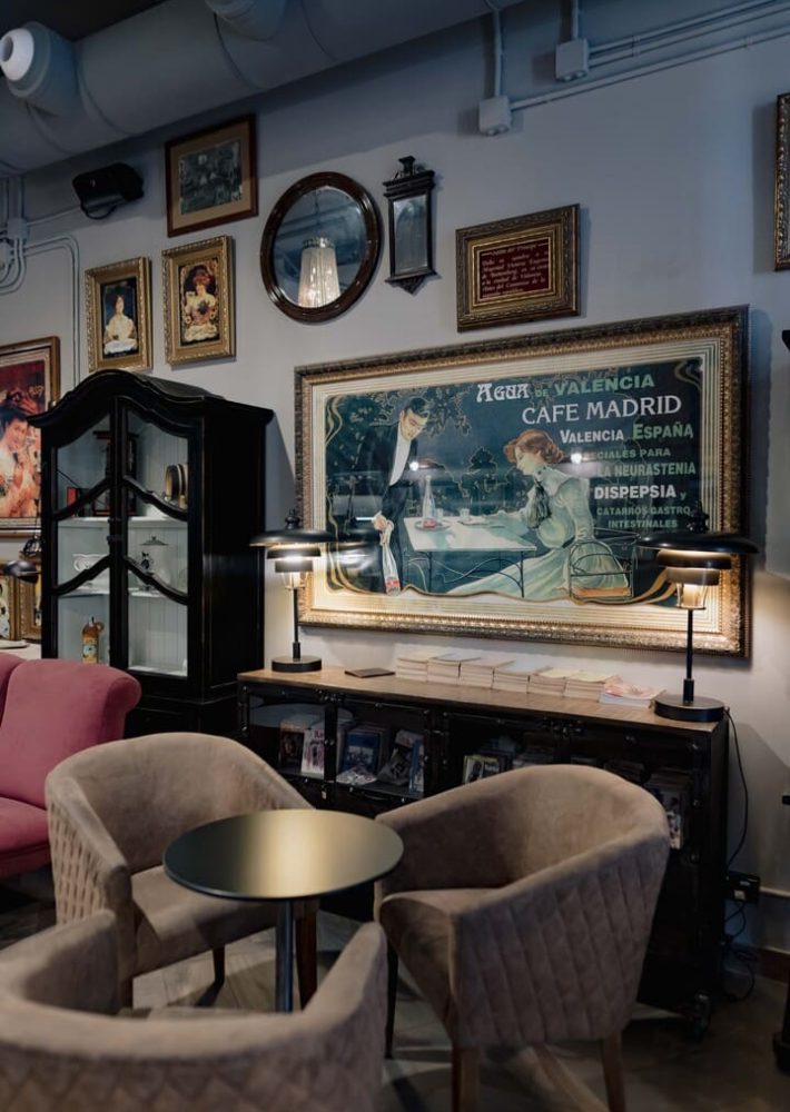 Interior del Café Madrid Valencia con sillones beige, mesa redonda y decoración vintage.