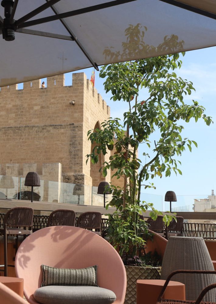Terraza de Luna Valencia con sillón rosa y plantas