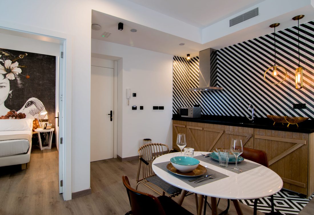 Cocina y comedor de suite con salpicadero a rayas negro/blanco y mesa con vajilla y copas