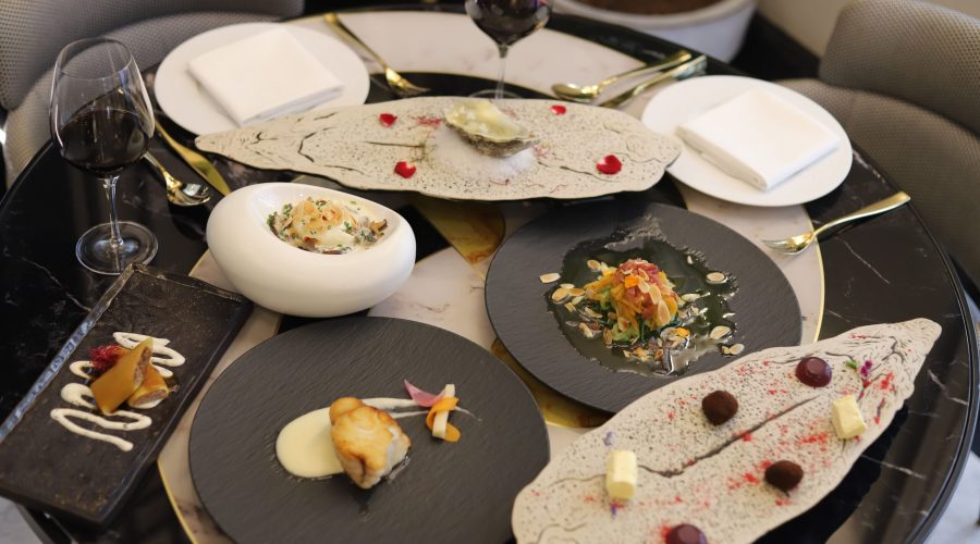 Menú degustación con varios platos presentados en mesa, copa de vino tinto