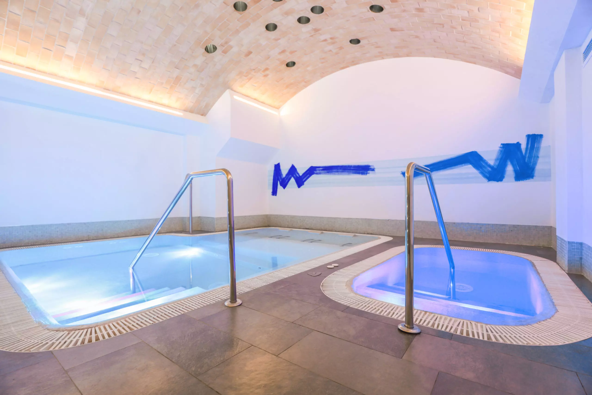 Piscina interna e vasca idromassaggio nello spa, parapetti in acciaio e soffitto a volta in mattoni