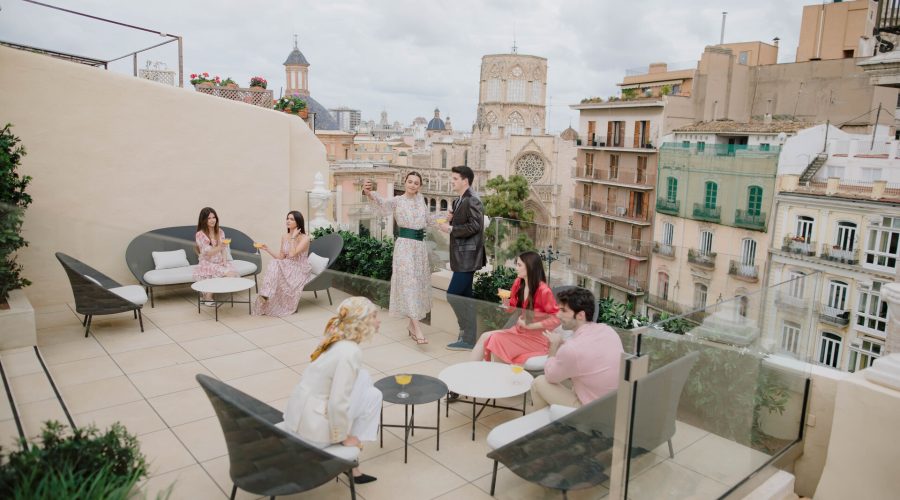 Terraza del Hotel Palacio Vallier con grupo de huéspedes brindando y vistas al casco antiguo.