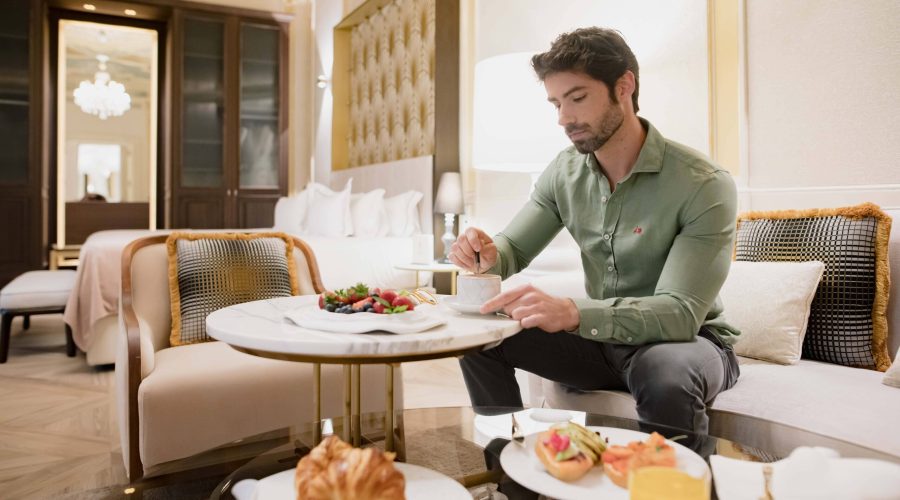 Hombre en sala de estar de hotel desayuna con servicio a la habitación