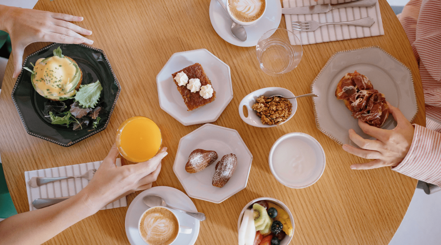 Desayuno variado en la mesa del Hotel Puerta Serranos: café, zumo de naranja, bollos, granola y fruta