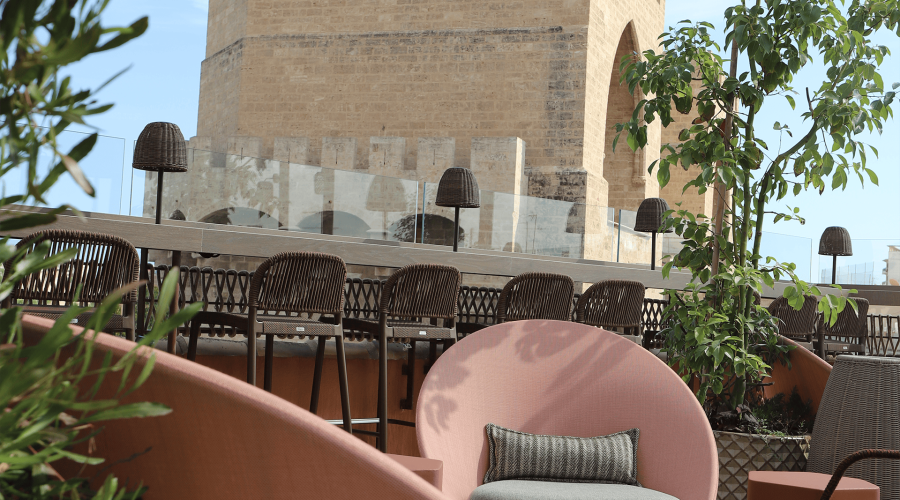 Terraza del Hotel Puerta Serranos con sillones de ratán y plantas